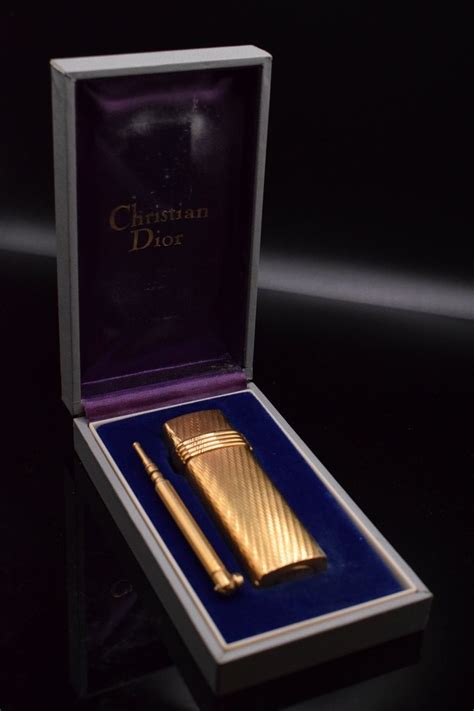 CHRISTIAN DIOR Briquet plaqué or texturé, signé au des